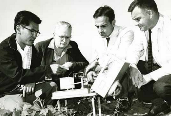 Four people looking at meteorological equipment.