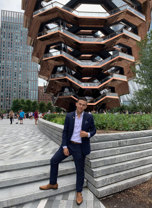 Luis Gasca standing in front of NYC attraction