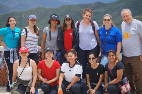  Group of students and a professor posing in front of mountains.