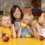 A teacher and three preschoolers having break for fruit.