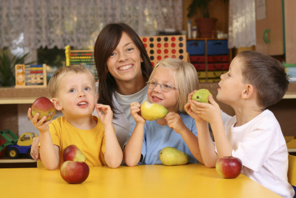 A teacher and three preschoolers having break for fruit.