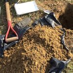 Shovel and pile of soil and hole in ground