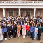 A group of smiling students stand in front of the Douglass Student Center.