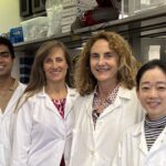 This is a zoomed-in image of four people in lab coats smiling in a lab.