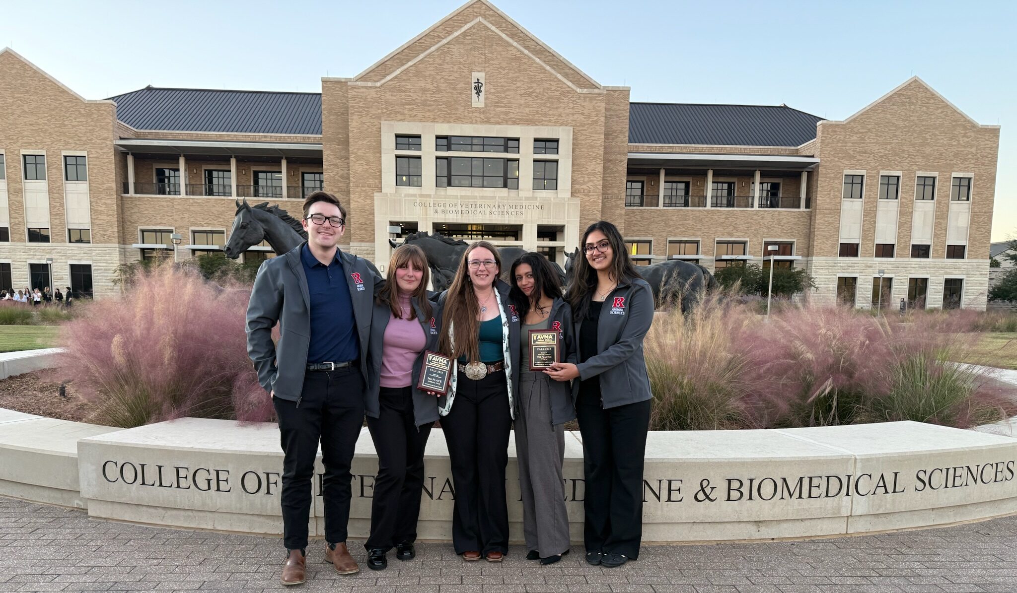 A group of five persons standing in front of a building
