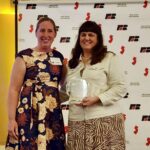 Two people pose for a picture together while one holds an award