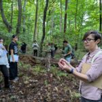 A faculty member and her students in a forest observing their surroundings