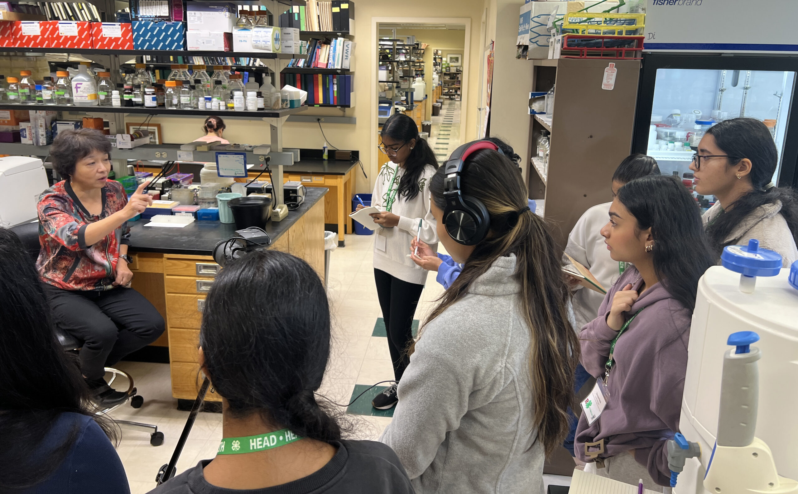High school students interact with a professor in a college laboratory