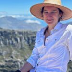 a person is photographed outdoors wearing a wide-brimmed hat