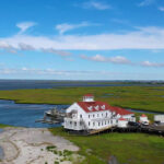 Aerial photo of a building surrounded by marshland and the encroaching ocean