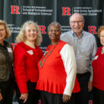 Several individuals pose for a group picture in from of a banner