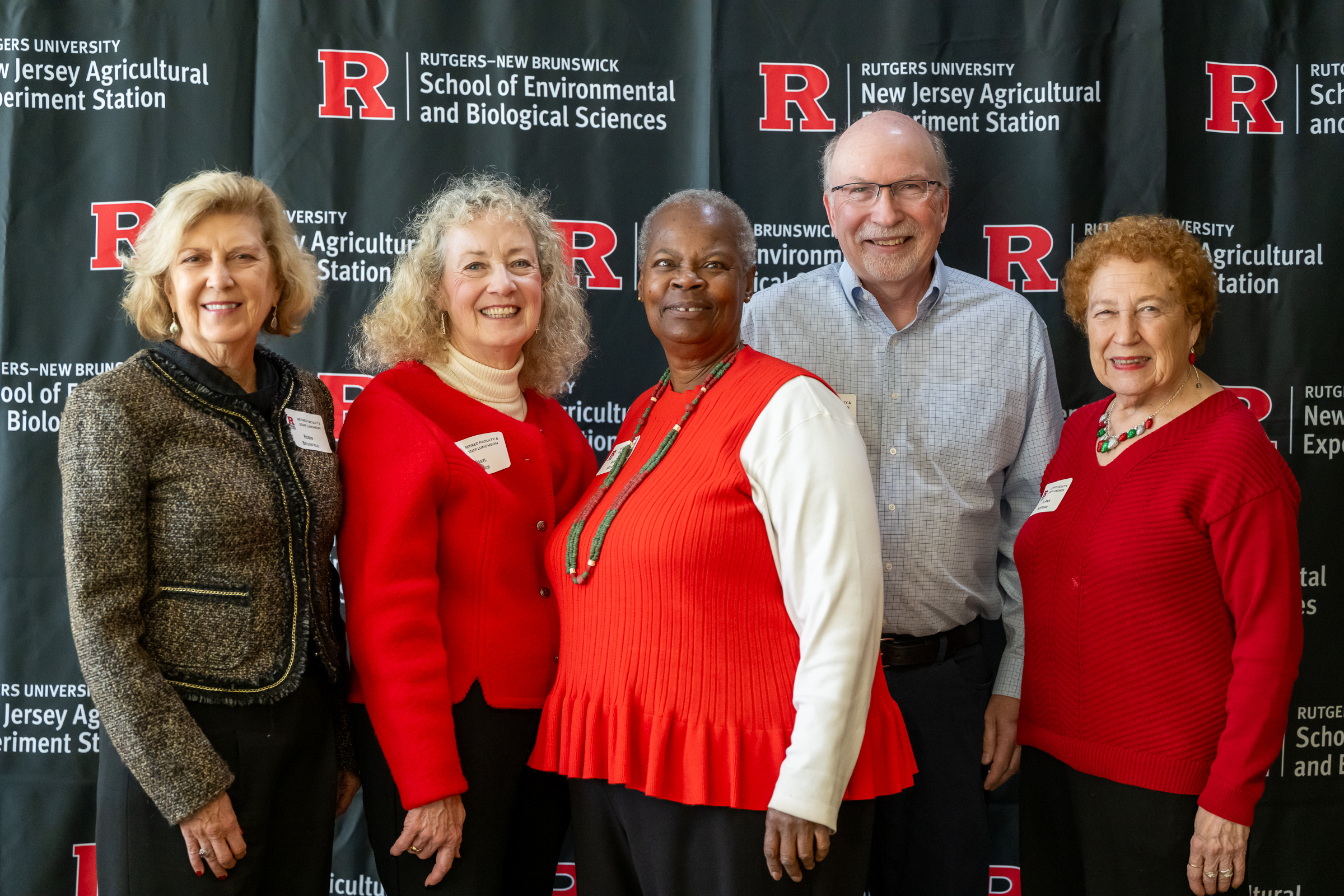 Several individuals pose for a group picture in from of a banner