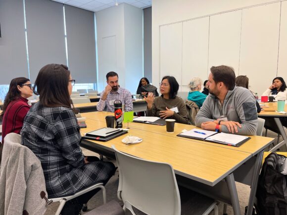 Five people sit around a table, mid-conversation.