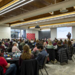 A room full of attendees at a conference listening to a presentation