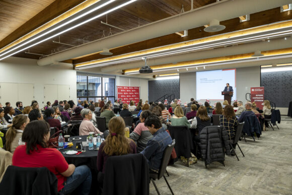 A room full of attendees at a conference listening to a presentation