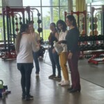Doctoral students demonstrating that strength training can be done with everyday household products, for those who don't have access to weights or a fitness facility. Here they are demonstrating with a full laundry detergent container.