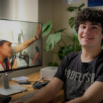 A person poses for a photo next to a computer