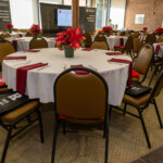 A room of tables set with cutlery, a flower on each table and Rutgers merchandise on each seat.