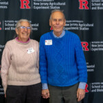 Two people posing for a photo together in front of a Rutgers University New Jersey Agricultural Experiment Station banner