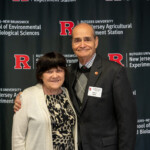 Two people posing for a photo together in front of a Rutgers University New Jersey Agricultural Experiment Station banner