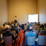 A presenter speaks to a group about the hay yield in 2024