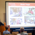 A presenter speaking to a group about goat yoga