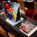 A seat at a table containing pamphlets and a tote bag that says Jersey Fresh