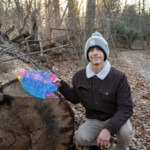 Person posing with leaf-shaped acrylic that has messages written on it
