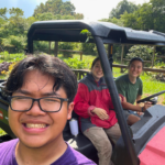 A person on the ground takes a selfie with two people in a golf cart