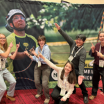 Five people pose for a picture with a poster at the conference