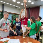 STEM Amb 2025 Newsroom Article - 1 Four students and a mentor work on a design challenge