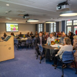 A person stands at a spodium and speaks at Joyce Carlson's retirement party.