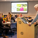A man speaks at a podium at Joyce Carlson's retirement party