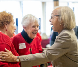 Three people standing in a circle, talking and smiling