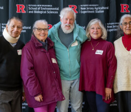 Several individuals pose for a group picture in from of a banner