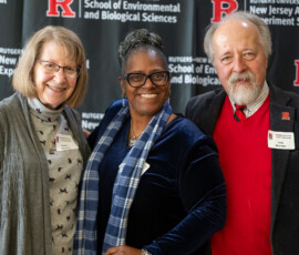 Three people pose for a picture in front of a Rutgers School of Environmental and Biological Sciences banner