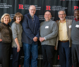 Several individuals pose for a group picture in from of a banner