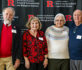Several individuals pose for a group picture in from of a banner